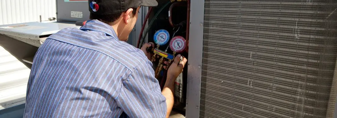 HVAC technician servicing a condenser unit in Corcoran