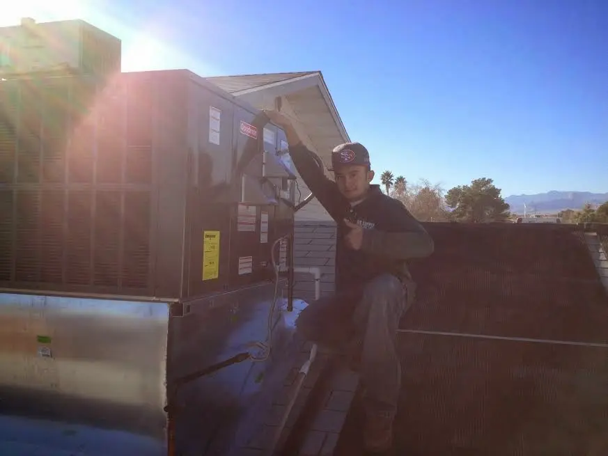 HVAC technician performing Air Duct Cleaning on a rooftop unit in Corcoran